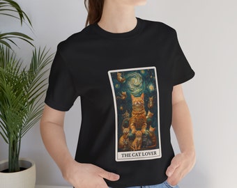 May include: Black t-shirt with a tarot card design. The card shows a large ginger cat with smaller cats, set against a starry night sky. The text "THE CAT LOVER" is displayed. The shirt is made of a soft material.