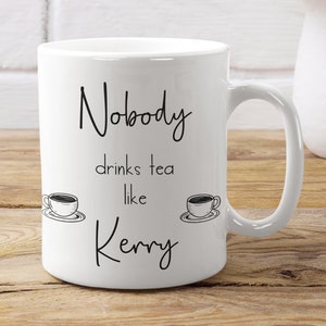 May include: White ceramic mug with black text that reads "Nobody drinks tea like Kerry" with two black and white illustrations of teacups on either side of the text.