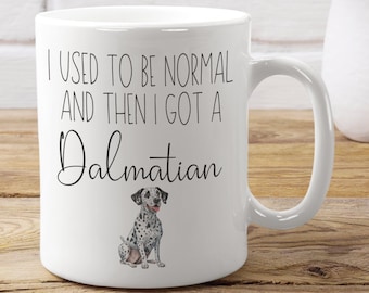 May include: White ceramic coffee mug with black text that reads "I used to be normal and then I got a Dalmatian". A black and white illustration of a Dalmatian dog is below the text.