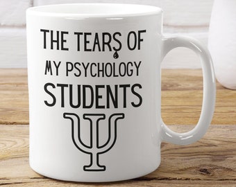 May include: White ceramic mug with black text that reads "The Tears of My Psychology Students" with a psychology symbol underneath.