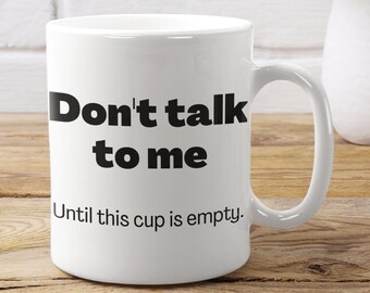 May include: White ceramic coffee mug with black text that reads "Don't talk to me Until this cup is empty."