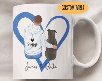 May include: White ceramic mug featuring a blue heart design with a person and a dog illustration. The person is wearing a hoodie with "I Staffys" printed on it. The names "James & Bella" are printed below the illustration. The mug is customizable.