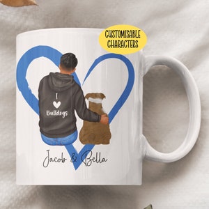 May include: White ceramic mug with a blue heart design. The heart is drawn around a man and a dog. The man is wearing a black hoodie with the words "I love bulldogs" on it. The text "Jacob & Bella" is written below the heart.