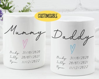 May include: Two white ceramic mugs with black lettering. One mug says "Mummy" with a pink heart and the other says "Daddy" with a blue heart. Both mugs have a list of names and dates printed below the heart.