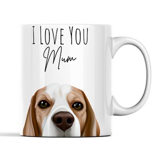 May include: White ceramic mug with a brown and white beagle dog peeking over the rim. The mug has the text "I love you Mum" printed on it.