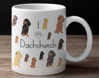 May include: White ceramic coffee mug with a design of various dachshund dogs in different colors and poses. The text "I love Dachshunds" is printed on the mug.
