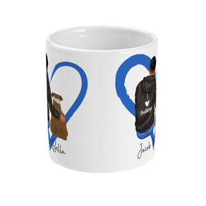 May include: White ceramic mug with a blue heart design. The heart is split in half with the names "Bella" and "Jacob" written on each side. The mug features a cartoon illustration of a couple holding hands.