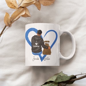 May include: White ceramic mug with a blue heart design. The heart features a cartoon illustration of a person with a dog. The mug has the text "I love Bulldogs" and "Jacob & Bella" printed on it.