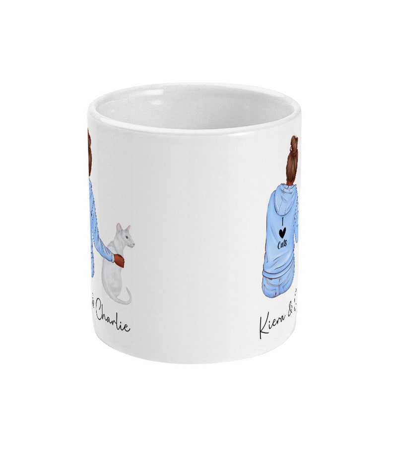 Może przedstawiać: Biały kubek ceramiczny z niebiesko-białym rysunkiem dw&oacute;ch kobiet i kota. Na kubku widnieje napis "Kiera & Charlie".