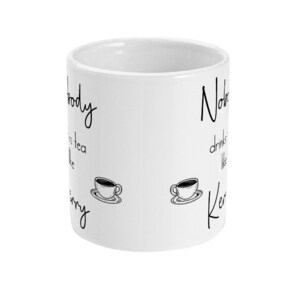 May include: White ceramic mug with black text that reads "Nobody drinks tea like Kerry" and "Nobody drinks tea like Kerry". The text is written in a cursive font. There are two black and white illustrations of coffee cups on the mug.