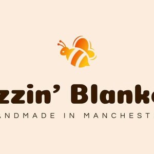 May include: The Buzzin' Blankets logo shows a cartoon bee in orange and yellow above the brand name in brown. Beneath, the text "HANDMADE IN MANCHESTER" is displayed, indicating the origin of the products.