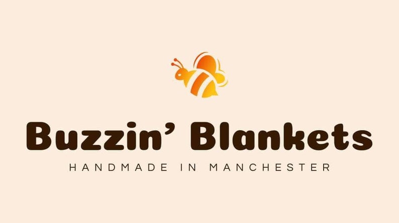 May include: The Buzzin' Blankets logo shows a cartoon bee in orange and yellow above the brand name in brown. Beneath, the text "HANDMADE IN MANCHESTER" is displayed, indicating the origin of the products.