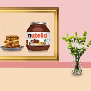 Peut inclure: Une impression encadrée représentant un pot de Nutella et une pile de gaufres au chocolat. Le pot de Nutella est marron avec le nom de la marque en blanc. Un vase de fleurs blanches et vertes est posé sur une table.