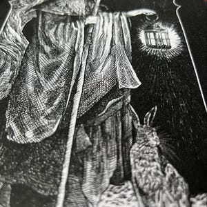 May include: A black and white graphic print on fabric featuring a bearded figure in a hooded robe holding a tall staff and a glowing lantern. Beside the figure stands a rabbit. The artwork uses detailed cross-hatching lines to create texture.