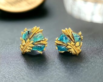 May include: A pair of gold earrings with blue and green enamel. The earrings are shaped like leaves and have a delicate design.