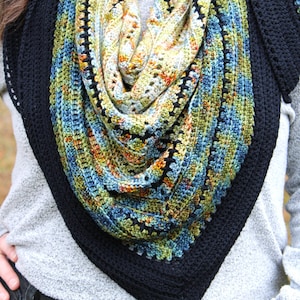 May include: A triangular crochet shawl with a colourful design. The shawl combines blue, green, yellow, and orange hues, framed by a solid black border. The detailed crochet work gives the shawl a textured and attractive appearance.