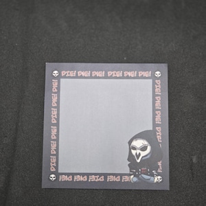 May include: A black and white illustration of a Reaper character from the video game Overwatch. The illustration is surrounded by a border with the text "DIE!" repeated multiple times.