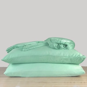 May include: A set of light green bedding, including a fitted sheet, flat sheet, and two pillowcases.