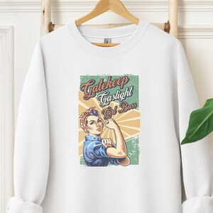 May include: White sweatshirt with the text "Gatekeep Gaslight Girl Boss" and a vintage-style illustration of a woman flexing her arm. The graphic features a woman in a blue shirt and red headscarf.