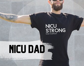 May include: A man wearing a black t-shirt with the text "NICU STRONG Dad Edition" printed on it. He is standing with his arms outstretched, wearing sunglasses and a black baseball cap.