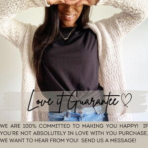 Op de afbeelding: Een vrouw draagt een witte, pluche cardigan over een zwart t-shirt en een blauwe jeans. De tekst "Love it Guarantee" is in zwart geschreven met een hartje. De tekst eronder luidt "We are 100% committed to making you happy! If you're not absolutely in love with your purchase, we want to hear from you! Send us a message!" met een logo dat "TSL" zegt.