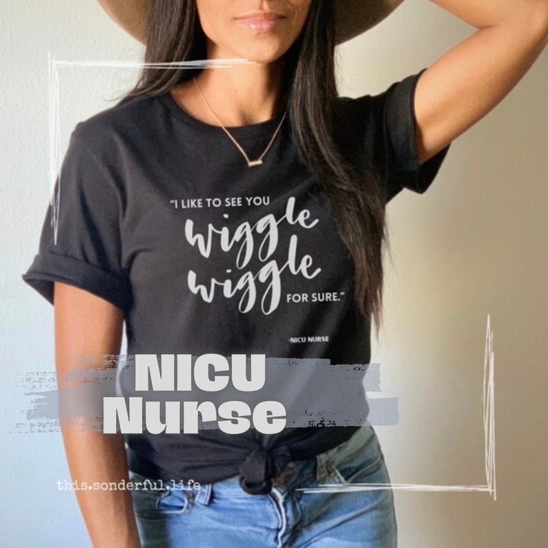 Op de afbeelding: Zwart T-shirt met witte tekst die luidt "Ik vind het leuk om je te zien wiebelen, zeker weten." De tekst is in een handschriftlijk lettertype. Onder de tekst staat de zin "NICU-verpleegkundige".