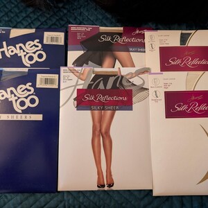 May include: Assortment of hosiery boxes. Two blue boxes of Hanes Too Day Sheers are next to four boxes of Hanes Silk Reflections. The Silk Reflections boxes feature images of legs and the words "Silky Sheer".