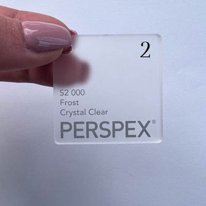 May include: A white frosted acrylic sheet with the text "S2 000 Frost Crystal Clear PERSPLEX" printed on it. The sheet is labeled with the number "2".
