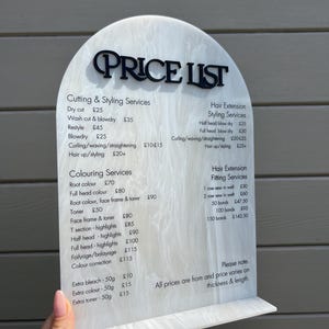 Puede incluir: Una lista de precios de sal&oacute;n de belleza en acr&iacute;lico blanco y negro. El letrero tiene una parte superior arqueada con la inscripci&oacute;n "PRICE LIST" en negro. La lista incluye servicios de corte, peinado, coloraci&oacute;n y extensiones de cabello.