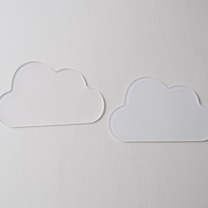May include: Two white acrylic cloud shapes on a white background.