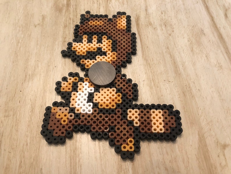 May include: A brown and white pixel art character with a brown hat and a black background. The character is running and has a brown and white striped tail.