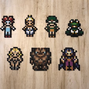 Peut inclure: Sept personnages d'art pixelisés colorés réalisés avec des perles. Les personnages sont une fille aux cheveux roux et une robe bleue, une fille aux cheveux blonds et une robe blanche, une créature verte avec un chapeau vert, une créature verte avec un chapeau blanc, une fille aux cheveux blonds et une robe noire, une créature brune aux yeux bleus et une créature violette avec un chapeau violet.