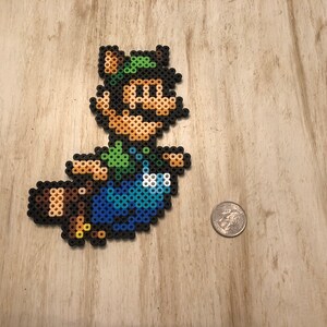 May include: A green, blue, and brown pixel art character of a video game character wearing a green hat and overalls. The character is holding a brown tail.