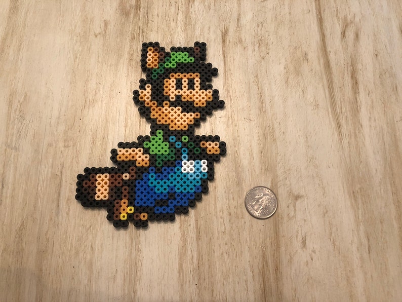 May include: A green, blue, and brown pixel art character of a video game character wearing a green hat and overalls. The character is holding a brown tail.