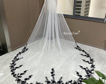 May include: A white bridal veil with a black floral lace trim. The veil is laid out on a white surface.