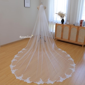 May include: A long, white bridal veil with a delicate lace trim. The veil is made of soft tulle and has a cathedral length.