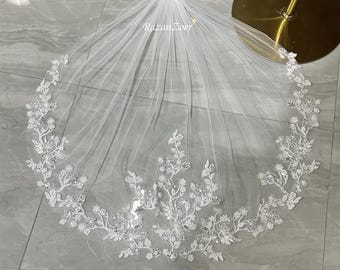 May include: White bridal veil with delicate floral lace embellishments. The lace features a vine design with small white flowers and sparkling accents.