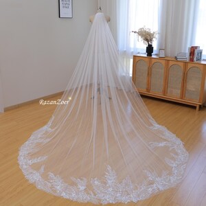 May include: A long, white bridal veil with a delicate lace trim. The veil is made of soft tulle and has a cathedral length.