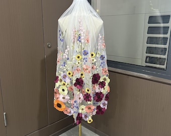 May include: White tulle fabric with embroidered flowers in shades of pink, yellow, orange, and purple. The flowers are 3D and have a realistic appearance.