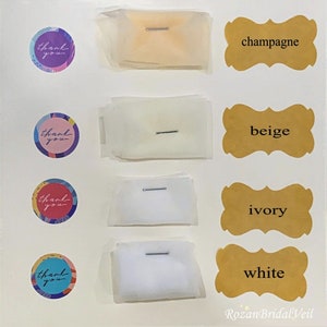 May include: Four swatches of tulle fabric in different colors: champagne, beige, ivory, and white. Each swatch is labeled with the color name and has a small pin attached to it.
