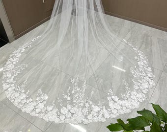 May include: A white bridal veil with a delicate floral lace trim. The veil is made of soft tulle and features a scalloped edge.