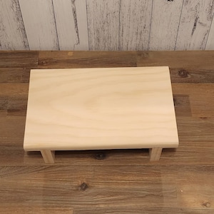 Puede incluir: Una plataforma simple de madera clara con una parte superior rectangular y cuatro patas. La plataforma est&aacute; hecha de madera sin terminar y tiene un patr&oacute;n de veta natural.