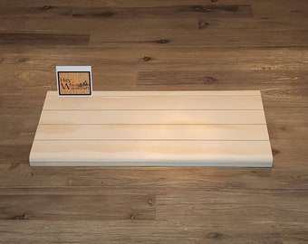 Puede incluir: Un estante de madera clara con un borde ligeramente redondeado. El estante está hecho de madera natural y tiene un acabado claro y natural. El estante está sobre un suelo de madera.