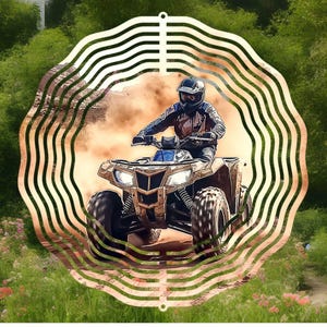 May include: A metal wind spinner with a circular design featuring a person riding an ATV on a dirt path. The spinner has a layered, wavy pattern in a gold color.