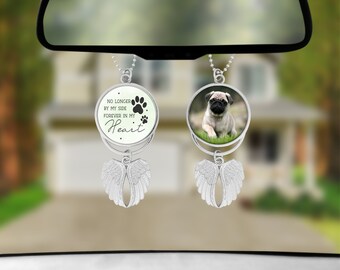 May include: A silver car charm with a round photo of a pug and a round charm with the text "No longer by my side, forever in my heart" and paw prints. The charms are attached to silver angel wings.