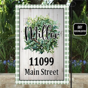 May include: A green and white gingham garden flag with a white wooden background. The flag features a green wreath with the name "Miller" in black text. The address "11099 Main Street" is also printed in black text.