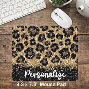 May include: A gold and black leopard print mouse pad with glitter accents. The mouse pad is 9.3 inches by 7.8 inches and has the word "Personalize" printed on it.