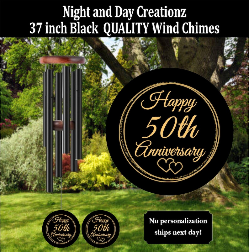 May include: Black wind chimes, 37 inches long, with a wooden top and accents. The chimes are displayed outdoors with a black circular sign that reads "Happy 50th Anniversary". Additional small signs with the same text are also visible.