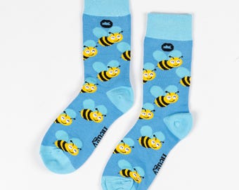 May include: A pair of blue socks with a pattern of yellow bees. The socks have a light blue cuff and the brand name "Truffy" is printed on the side.