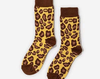 Könnte beinhalten: Ein Paar Crew-Socken mit gelbem Hintergrund und braunem Leopardenmuster. Zehen, Ferse und Bündchen sind braun. Die Socken sind aus einem weichen, bequemen Material.